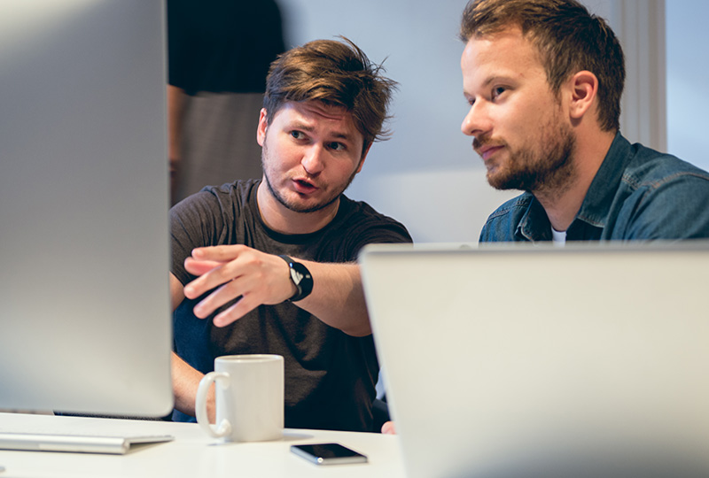 Two colleagues having a meeting in front of a computer monitor